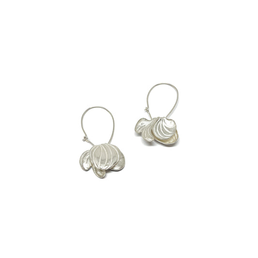 A pair of silver hoop earrings featuring textured, abstract floral or shell-like shapes dangling from the loops.
