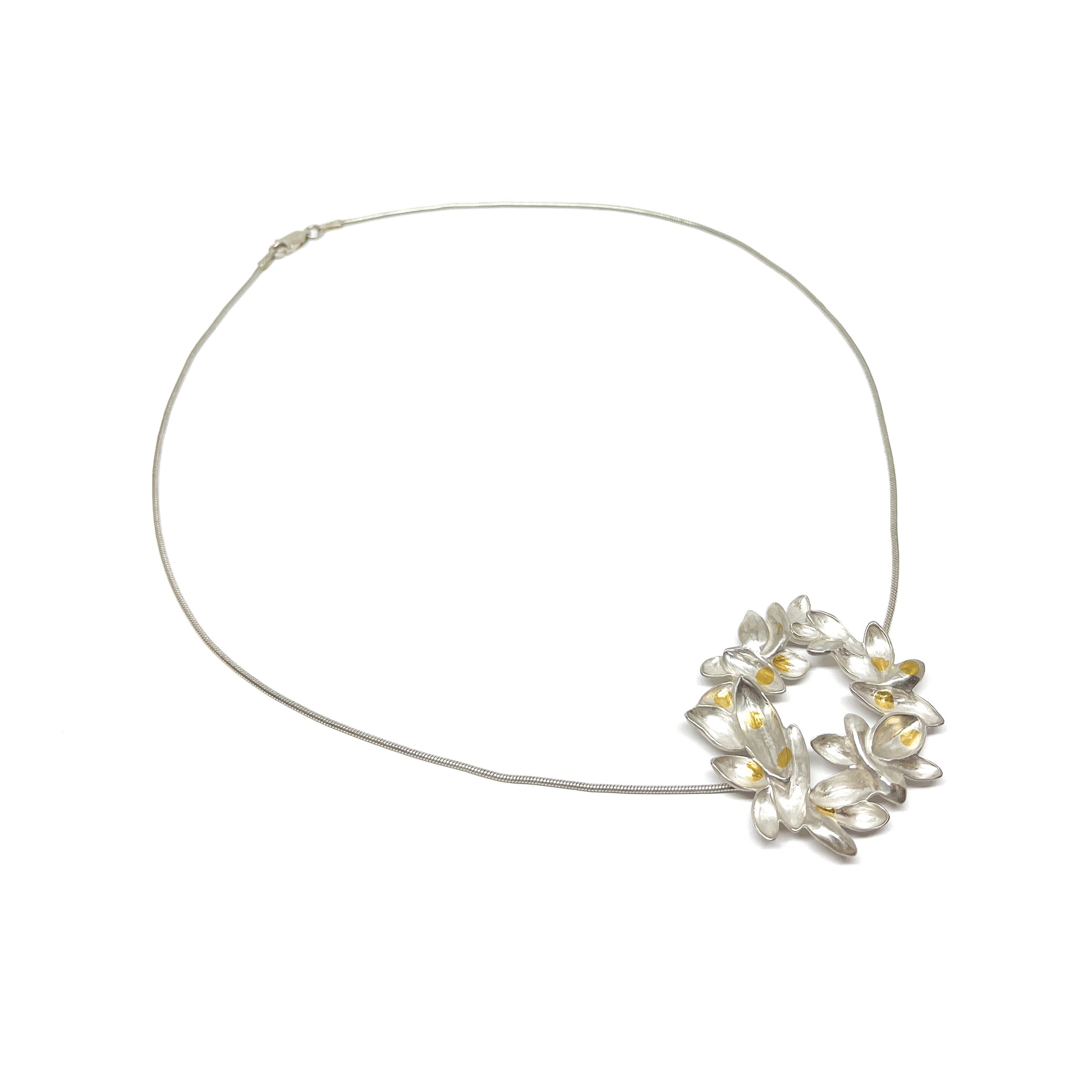 A silver wire necklace featuring a circular pendant of textured, abstract floral or lily-like shapes with Keum-Boo gold accents.