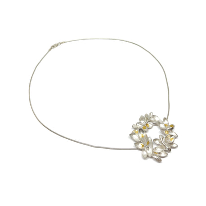A silver wire necklace featuring a circular pendant of textured, abstract floral or lily-like shapes with Keum-Boo gold accents.