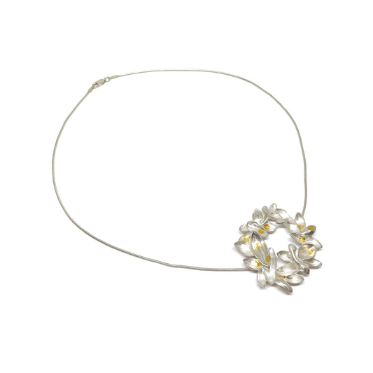 A silver wire necklace featuring a circular pendant of textured, abstract floral or lily-like shapes with Keum-Boo gold accents.