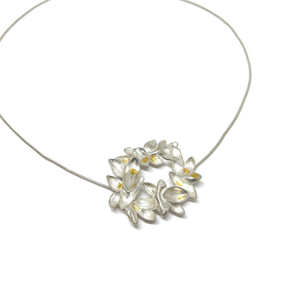 Silver snake chain necklace with a circular pendant of textured, abstract lily-like shapes and Keum-Boo gold accents.