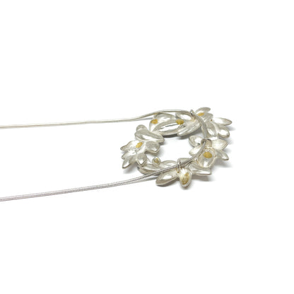 A silver snake chain necklace featuring a circular pendant of textured, abstract floral shapes with small Keum-Boo gold details.