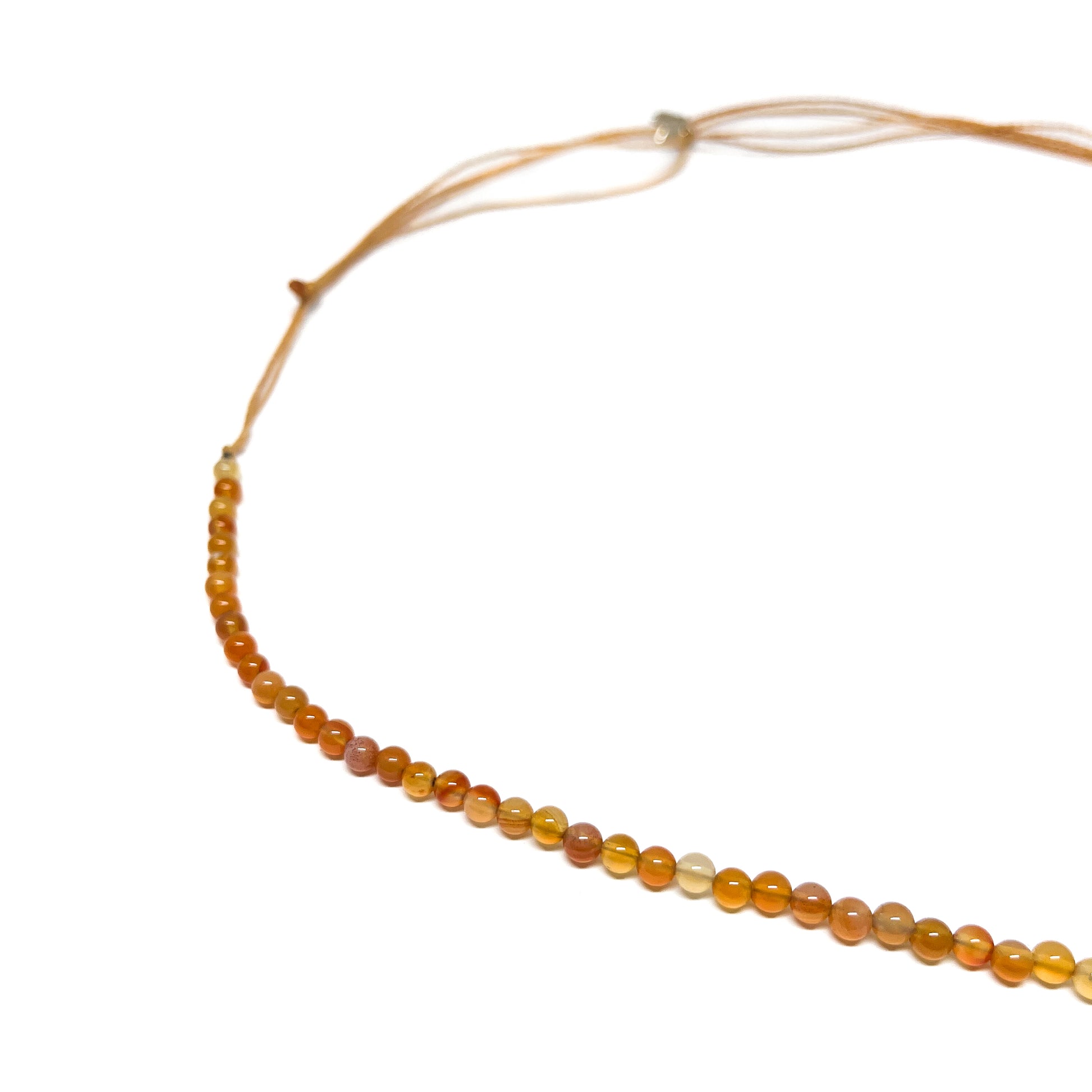 A delicate Hessonite Garnet Constellation Bracelet featuring small, round orange beads strung on a thin cord with adjustable ties.