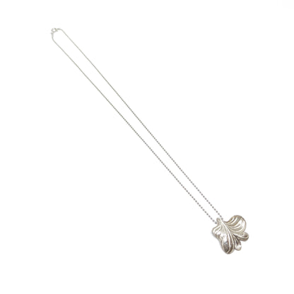 A long silver necklace featuring a large, textured pendant in an abstract floral or leaf-like shape.