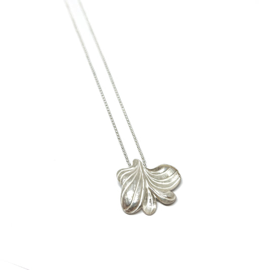 A silver necklace featuring a large, textured abstract floral or leaf-shaped pendant on a delicate chain.