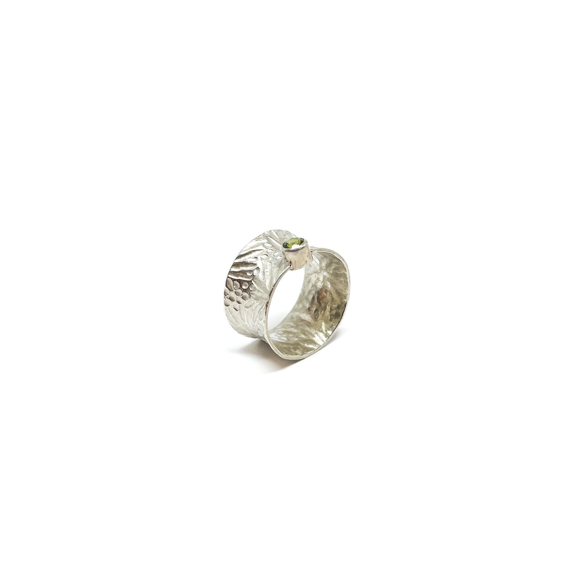 Textured sterling silver spinner ring featuring a single, oval-cut peridot gemstone.