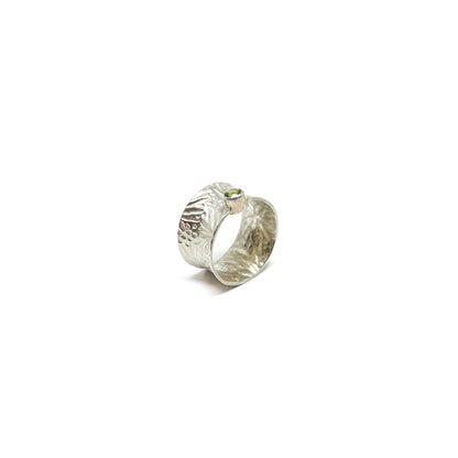 Textured sterling silver spinner ring featuring a single, oval-cut peridot gemstone.