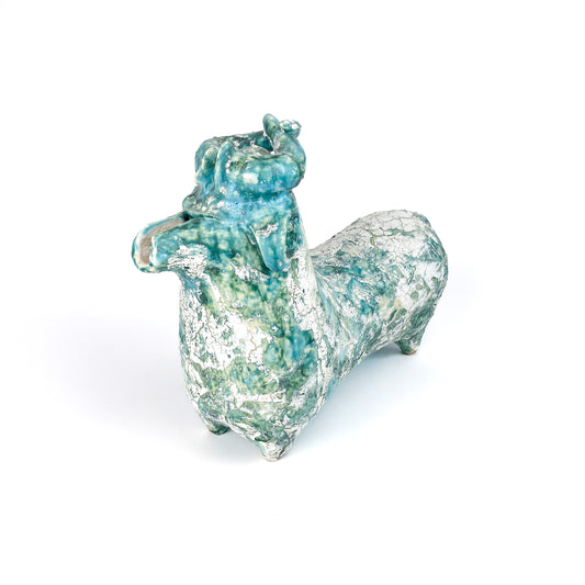 A textured ceramic bull figurine with a teal and white mottled glaze, raised head, and curled horns.