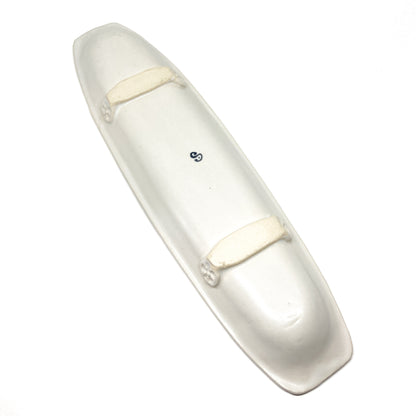 A long, narrow, white olive dish with raised details and a blue "S" in the center.