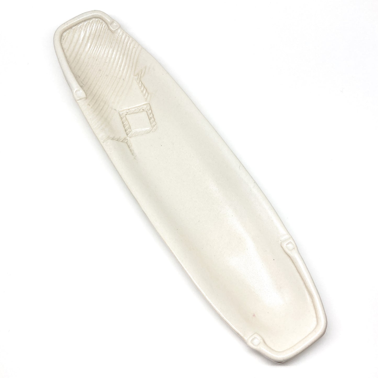 A long, narrow, white olive dish with embossed details, including a diamond shape.