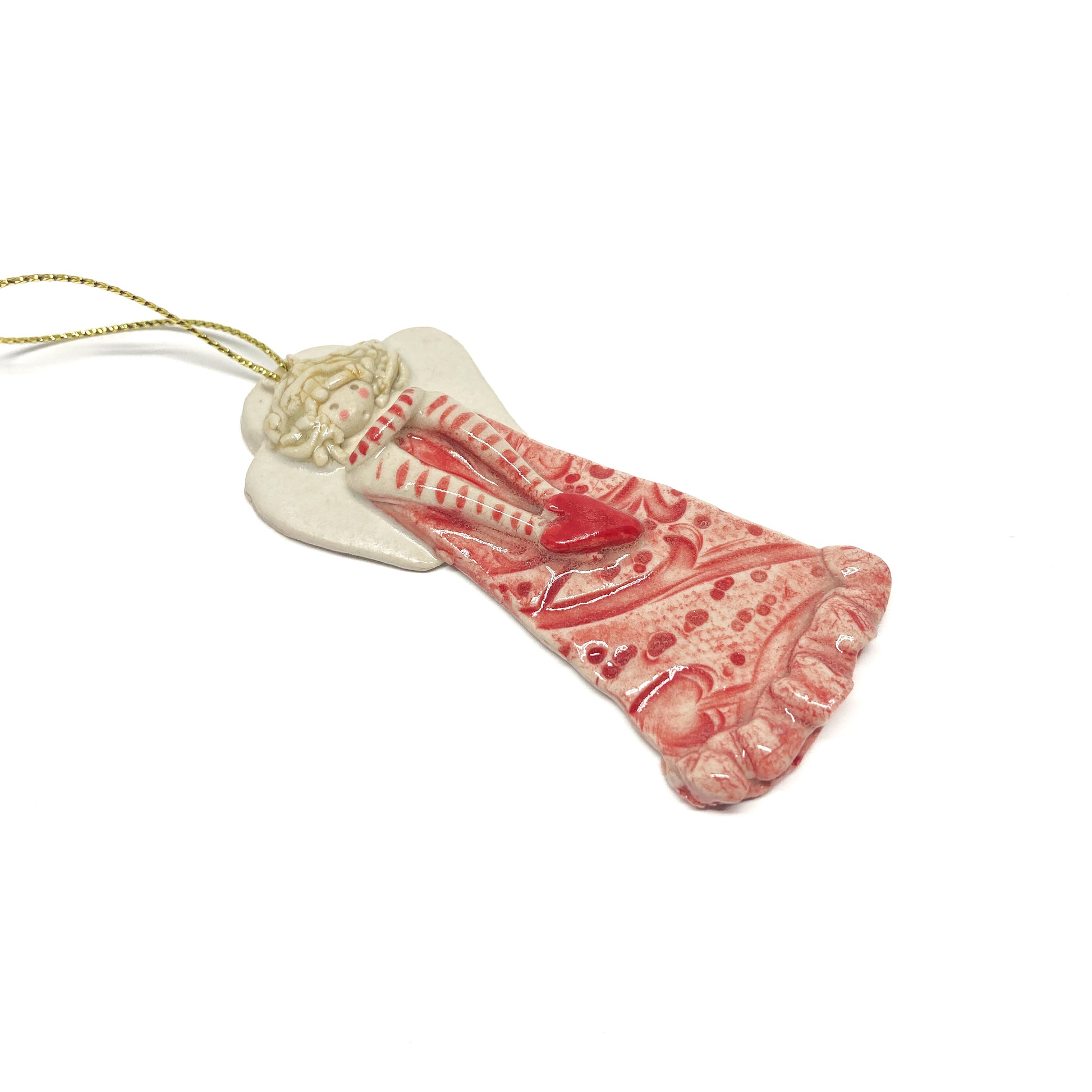A pink angel ornament with a heart and a gold string.