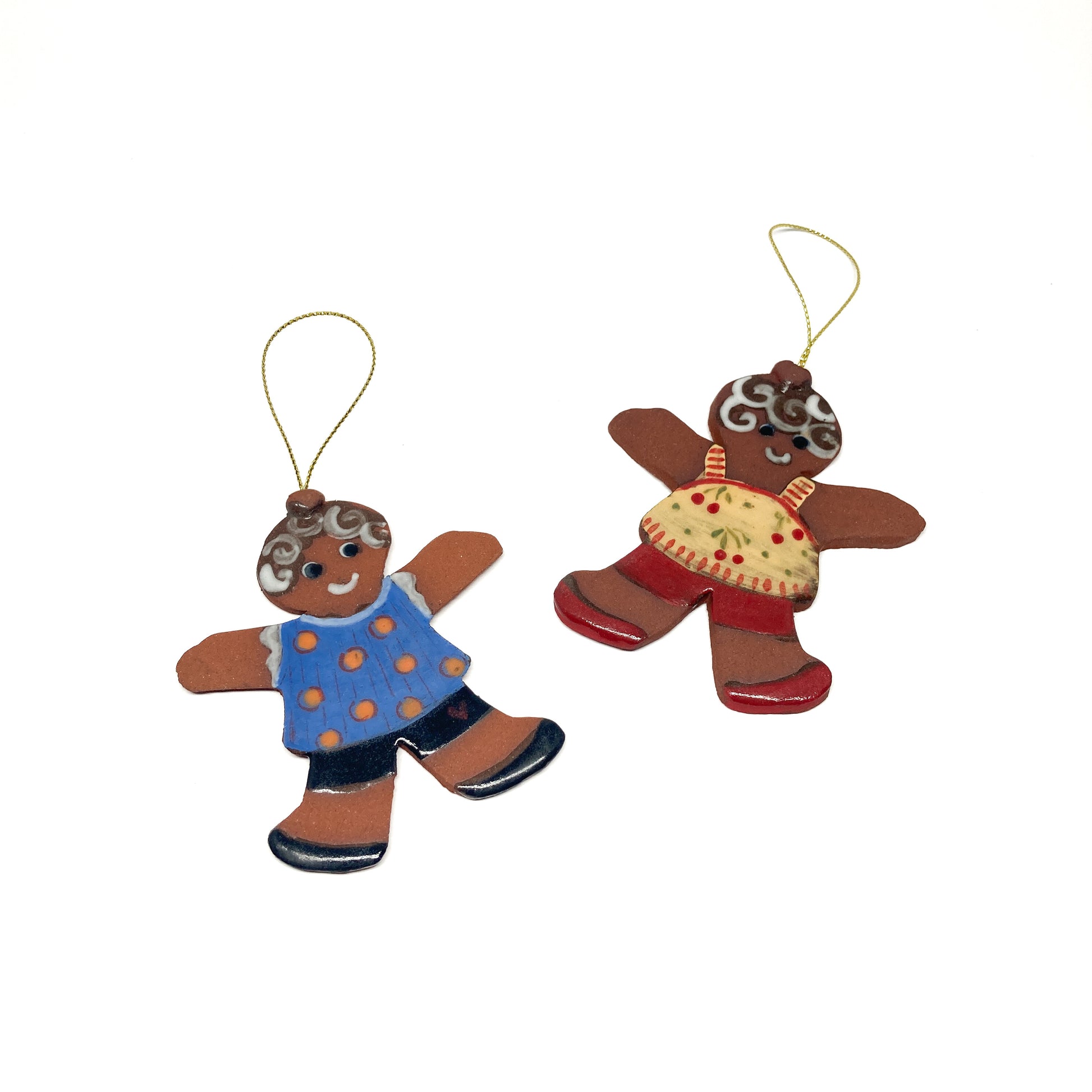 Two gingerbread girl ornaments with colorful outfits and gold strings.