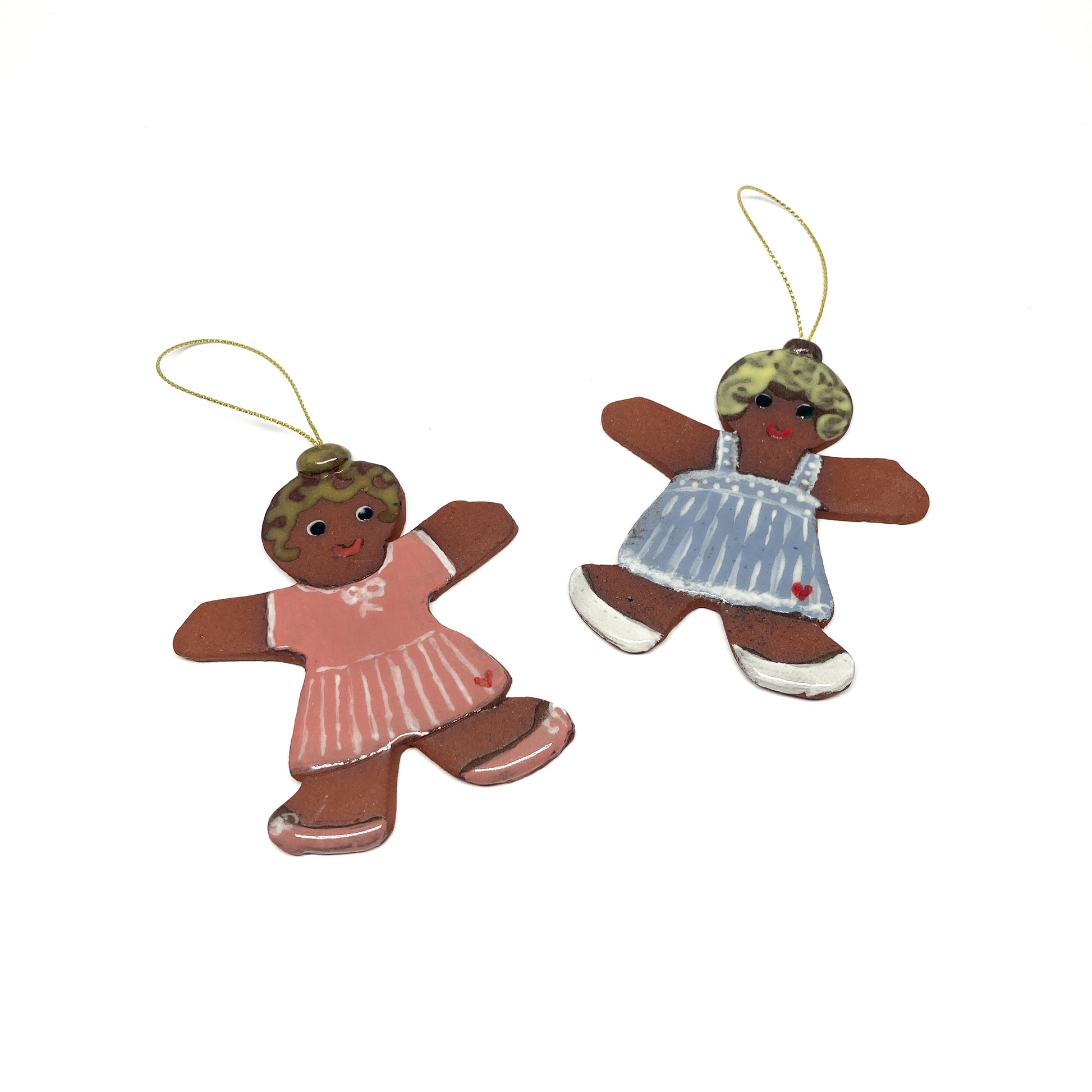 Two gingerbread girl ornaments with dresses and gold strings.