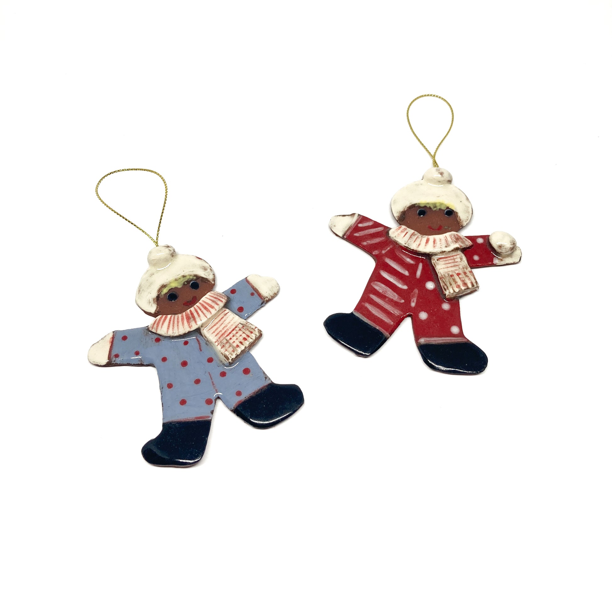 Two gingerbread man ornaments with winter outfits and gold strings.