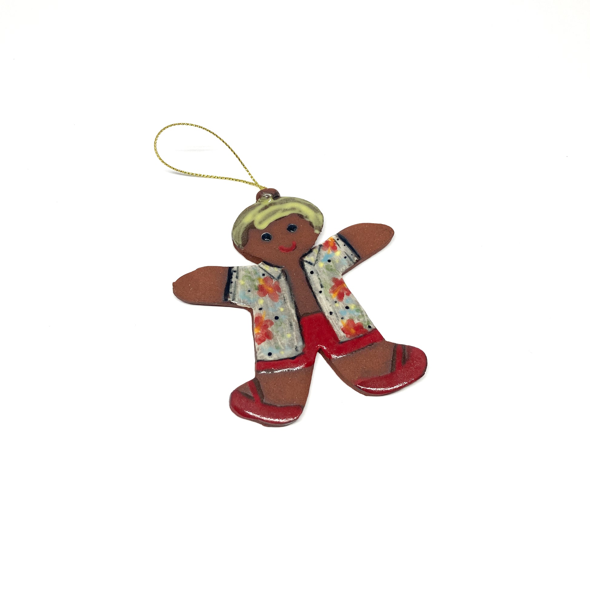 A gingerbread man ornament with a patterned shirt and a gold string.