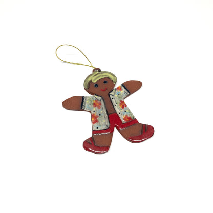 A gingerbread man ornament with a patterned shirt and a gold string.