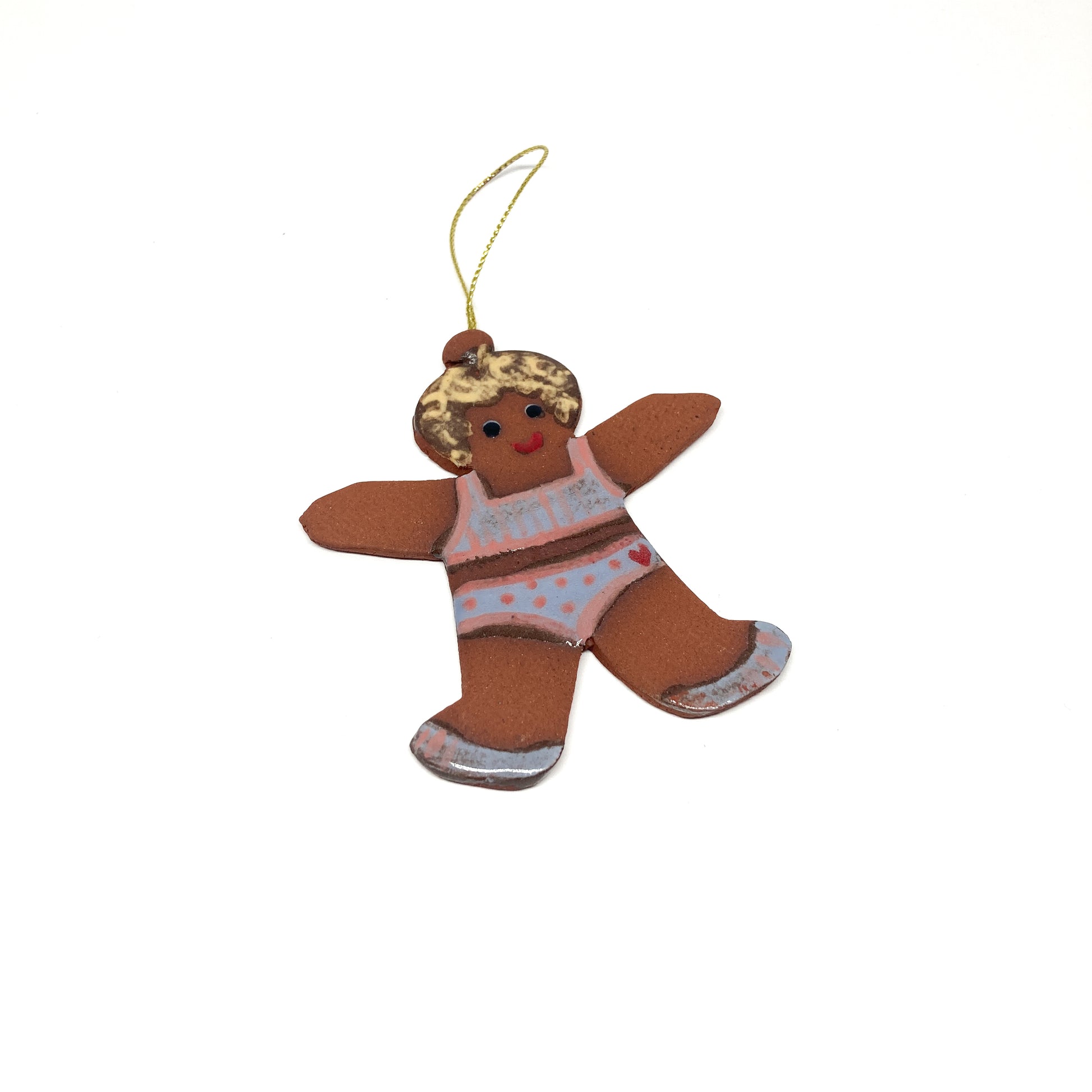 A gingerbread girl ornament with a patterned outfit and a gold string.