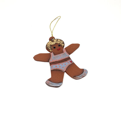 A gingerbread girl ornament with a patterned outfit and a gold string.