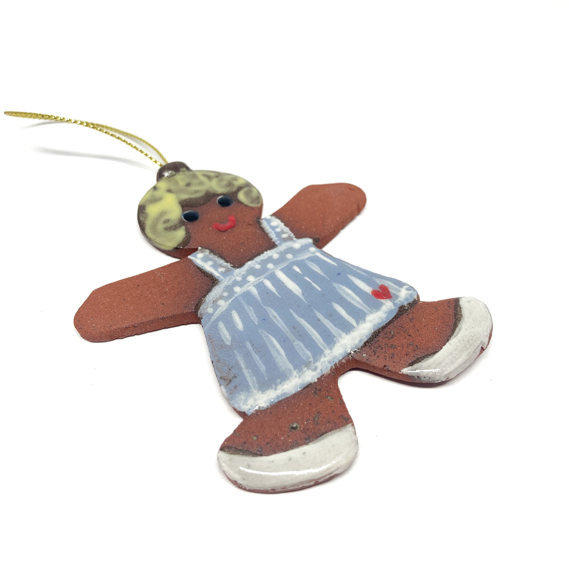A gingerbread girl ornament with a blue dress and a gold string.