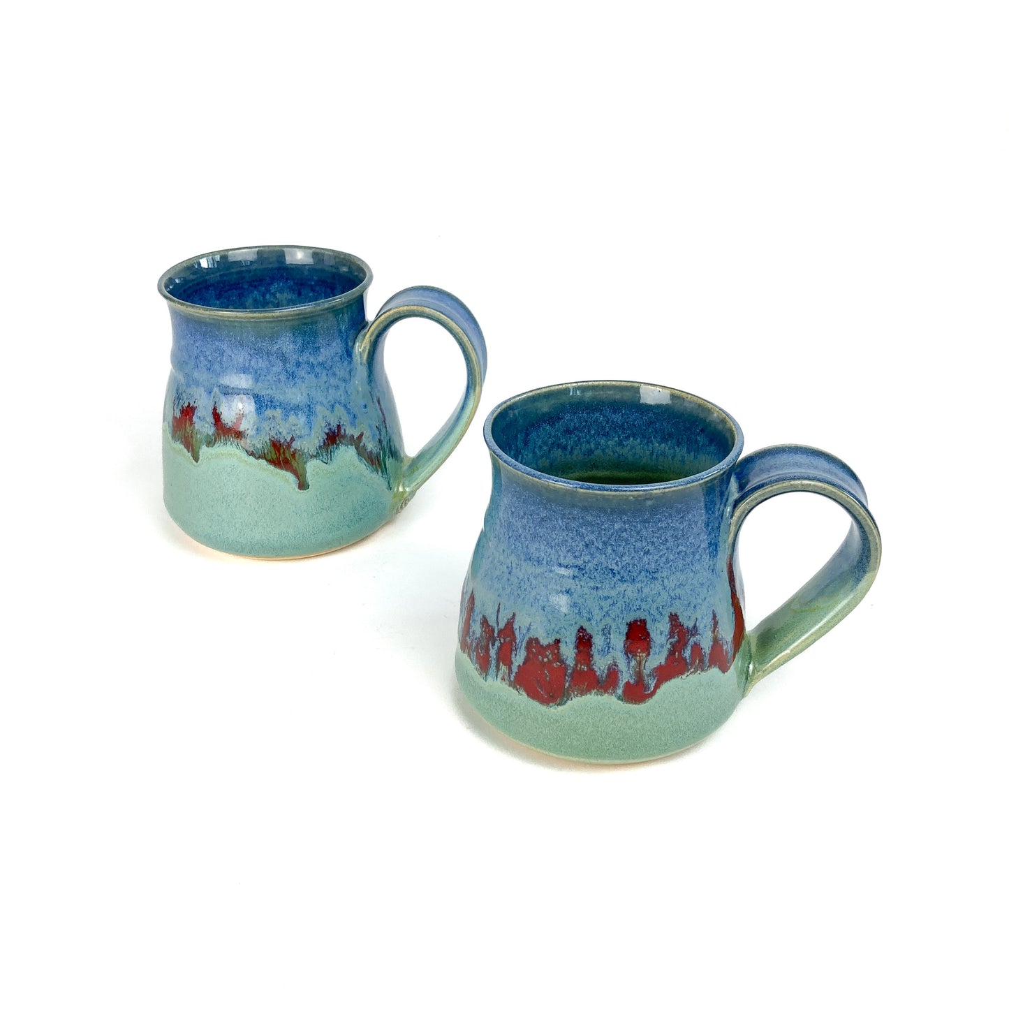 Two ceramic mugs with a blue-to-green gradient and red accents, viewed from a slightly angled perspective.
