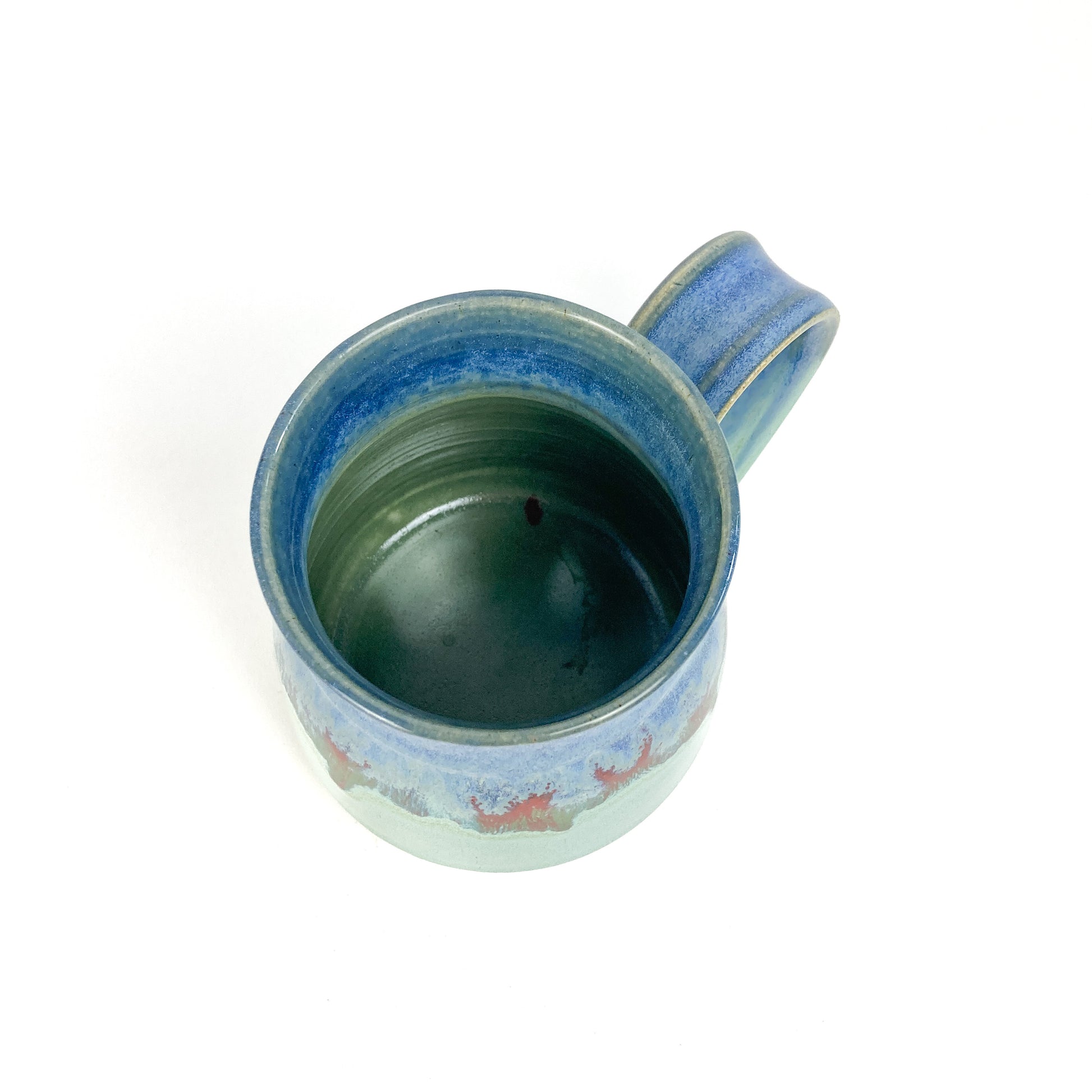 Top-down view of a ceramic mug with a blue-to-green gradient and red accents.