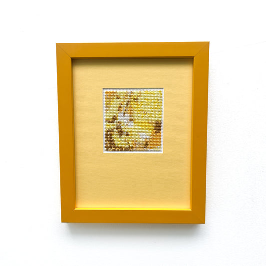 Framed "Yellow Monochrome" cross-stitch. A small square of stitched art is centered on a larger yellow mat within a yellow frame.