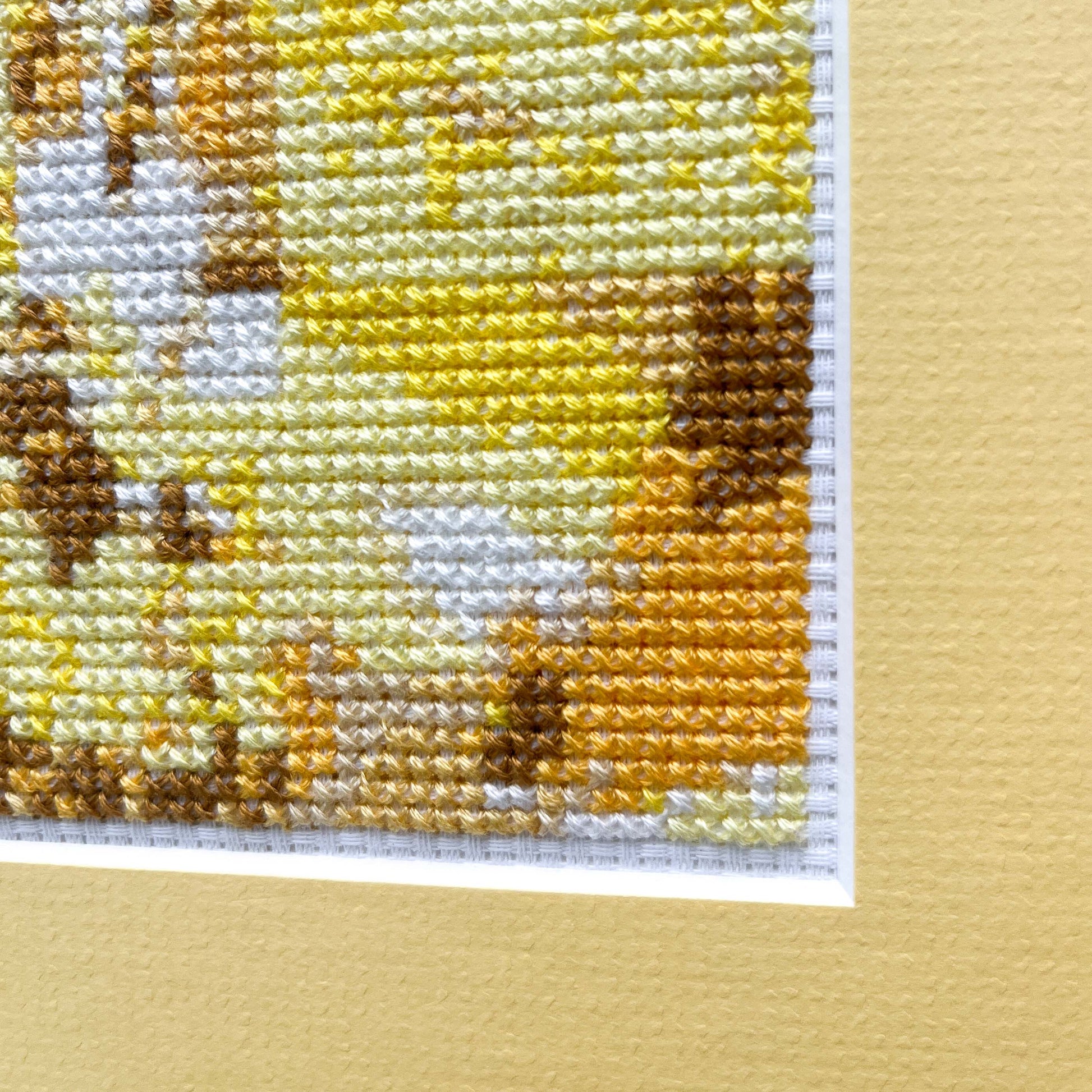 Close-up of the "Yellow Monochrome" cross-stitch. The stitching shows variations of yellow and brown.