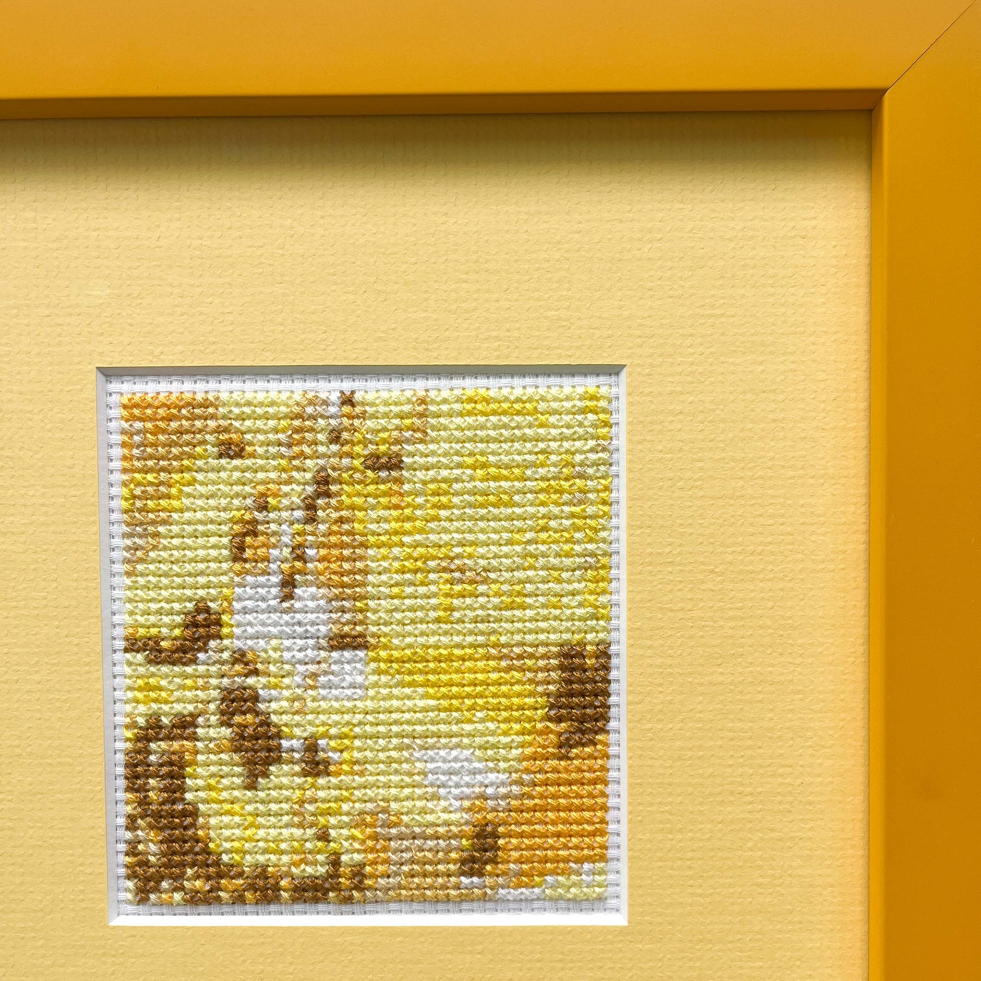 Cropped view of a framed "Yellow Monochrome" cross-stitch. The stitched art is on a mat within a visible portion of the frame.