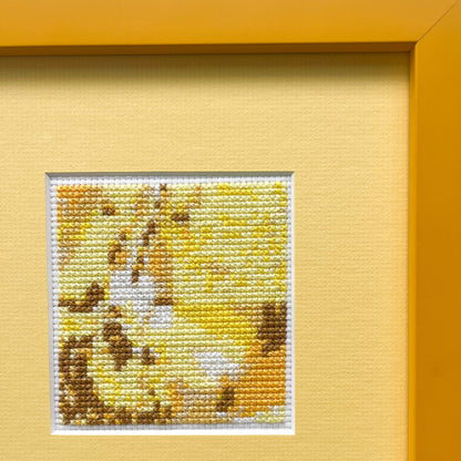 Cropped view of a framed "Yellow Monochrome" cross-stitch. The stitched art is on a mat within a visible portion of the frame.