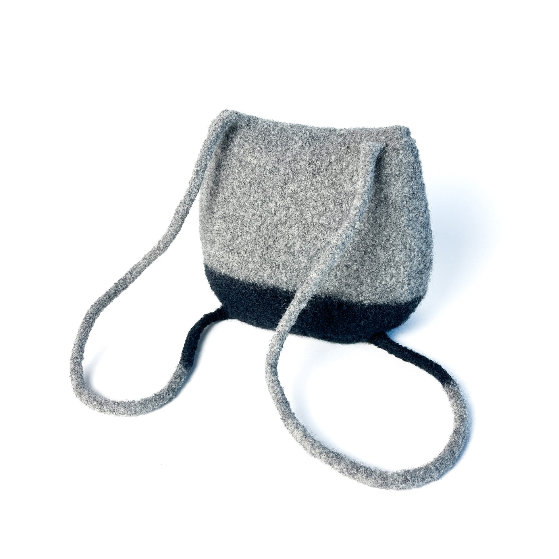 Two-tone felted backpack with a rounded shape and thin, looped shoulder straps. The back of the bag is visible.