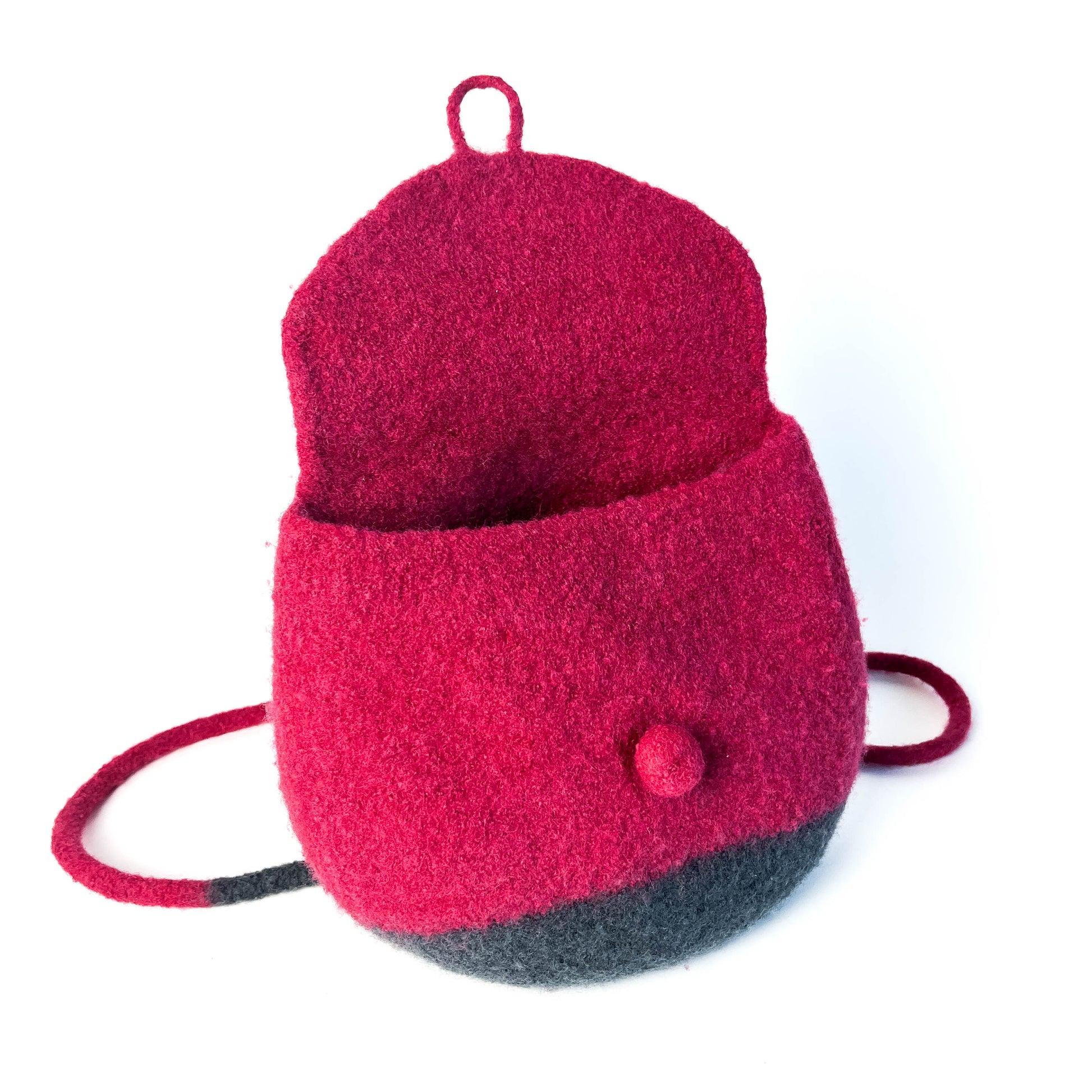 Open, two-tone felted backpack with a button detail and thin shoulder straps. The upper portion is a vibrant color.