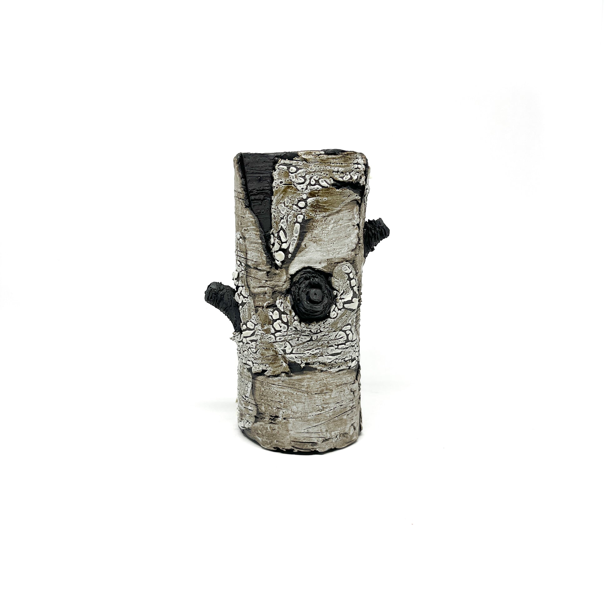 A cylindrical vase resembling birch bark with a textured surface, featuring black and white elements and two protruding branch-like details.