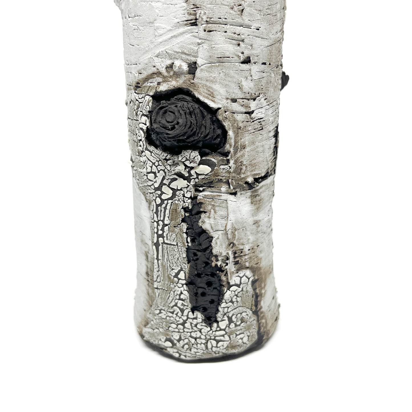 A close-up view of a cylindrical vase resembling birch bark with a textured surface, featuring black and white elements.