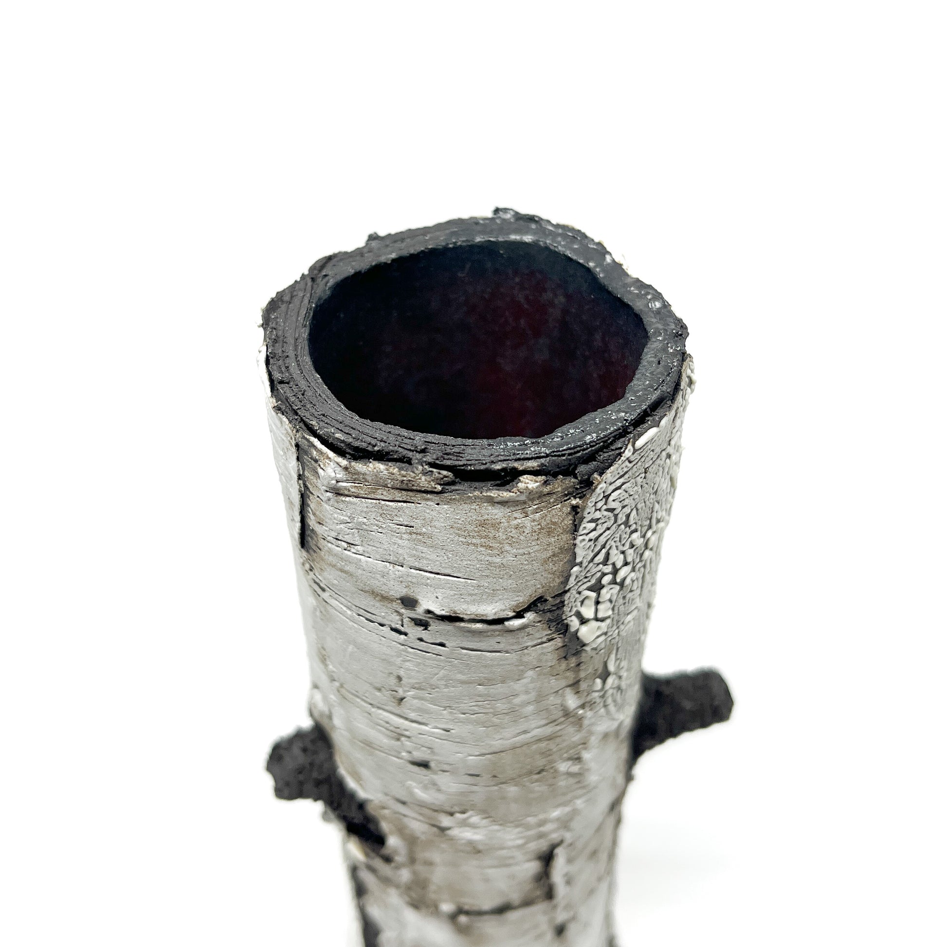 A cylindrical vase resembling birch bark with a textured surface, showing the opening at the top and a protruding element.