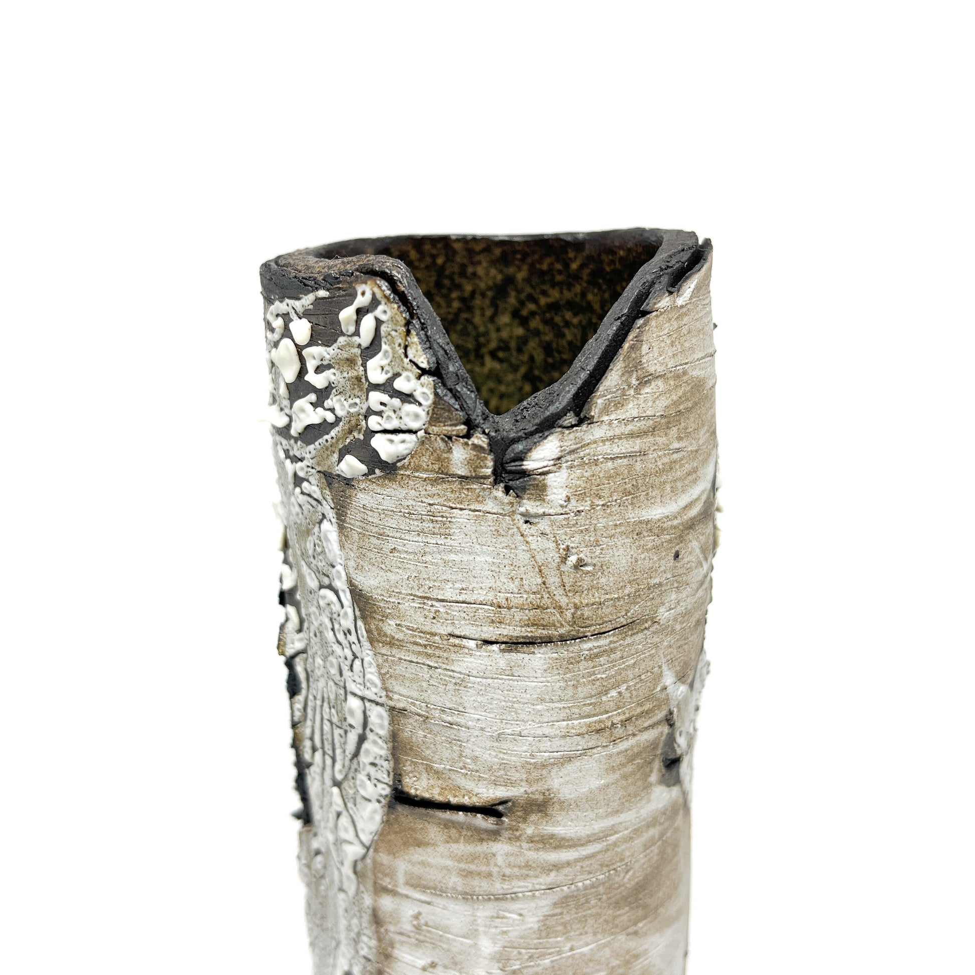 A close-up view of a tall, cylindrical vase resembling birch bark with a textured surface and a triangular opening at the top.