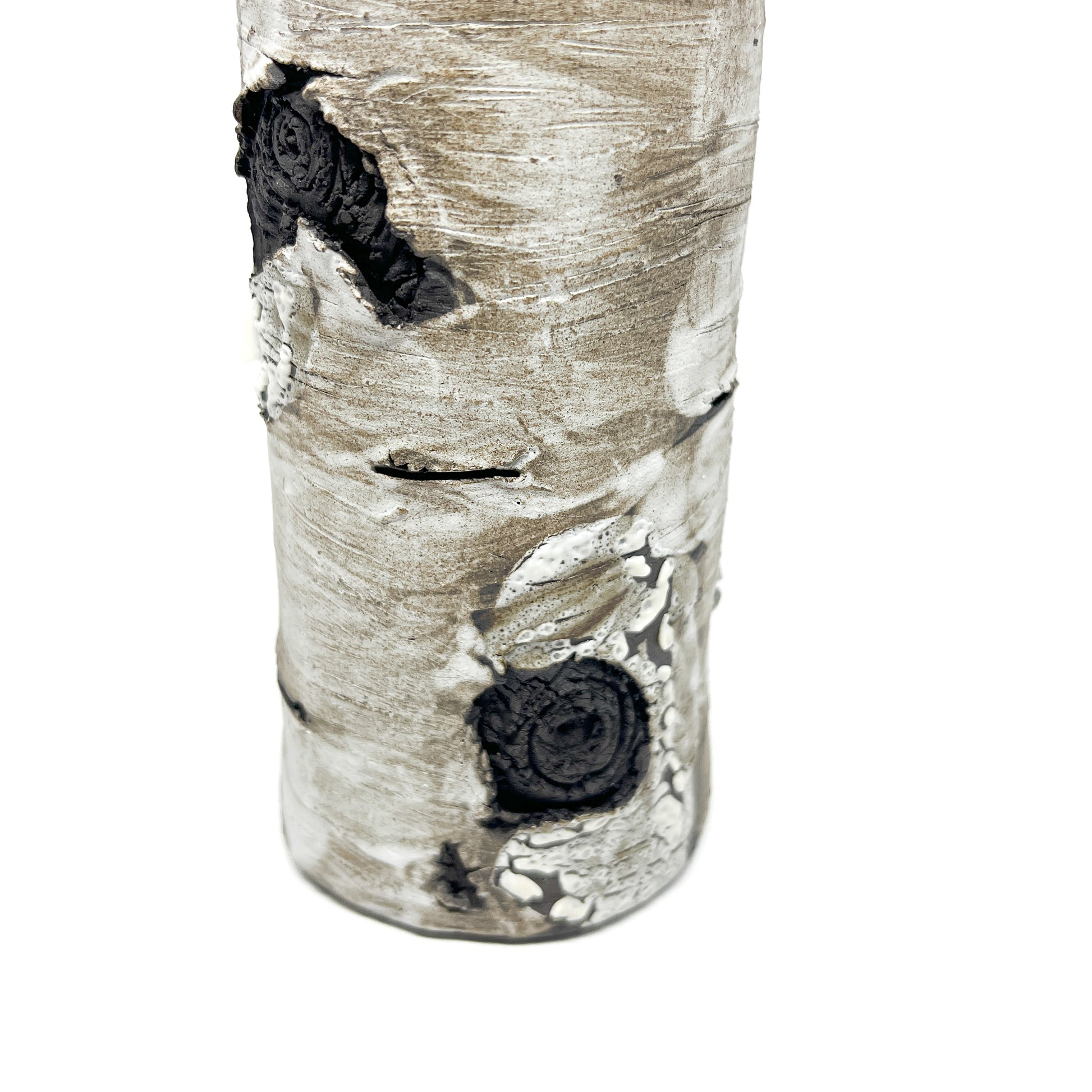 A close-up view of a tall, cylindrical vase resembling birch bark with a textured surface, featuring black and white elements.