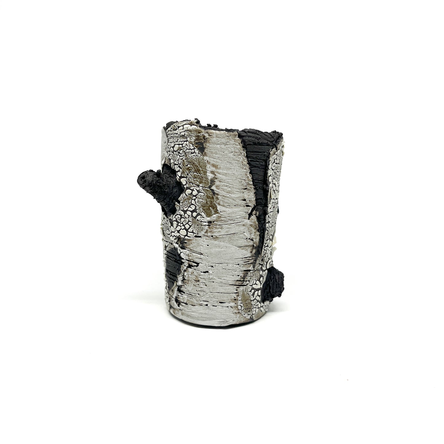 A cylindrical vase resembling birch tree bark, with black and white textured surfaces and a protruding branch-like element.