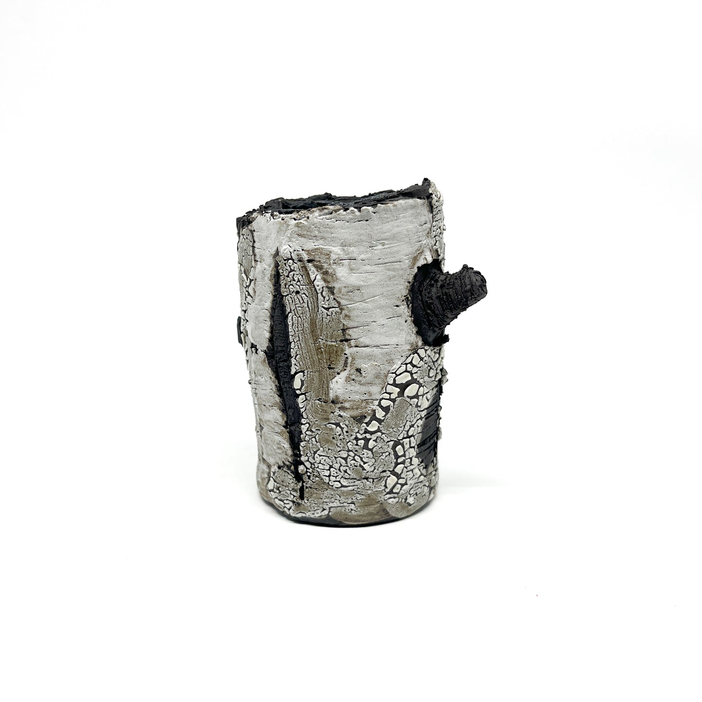 A cylindrical vase resembling birch tree bark with a textured surface, featuring black and white elements and a protruding branch-like detail.