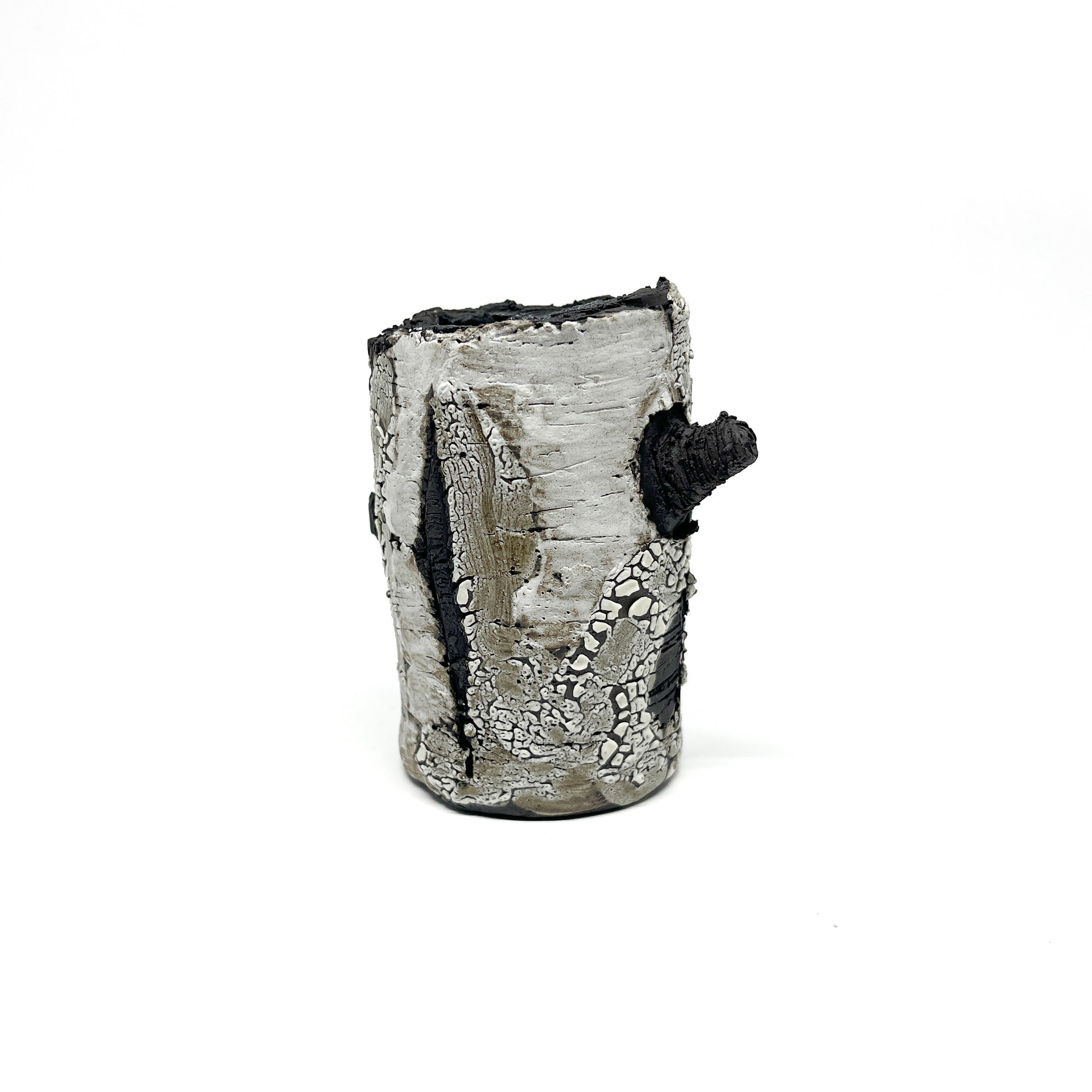 A cylindrical vase resembling birch tree bark with a textured surface, featuring black and white elements and a protruding branch-like detail.