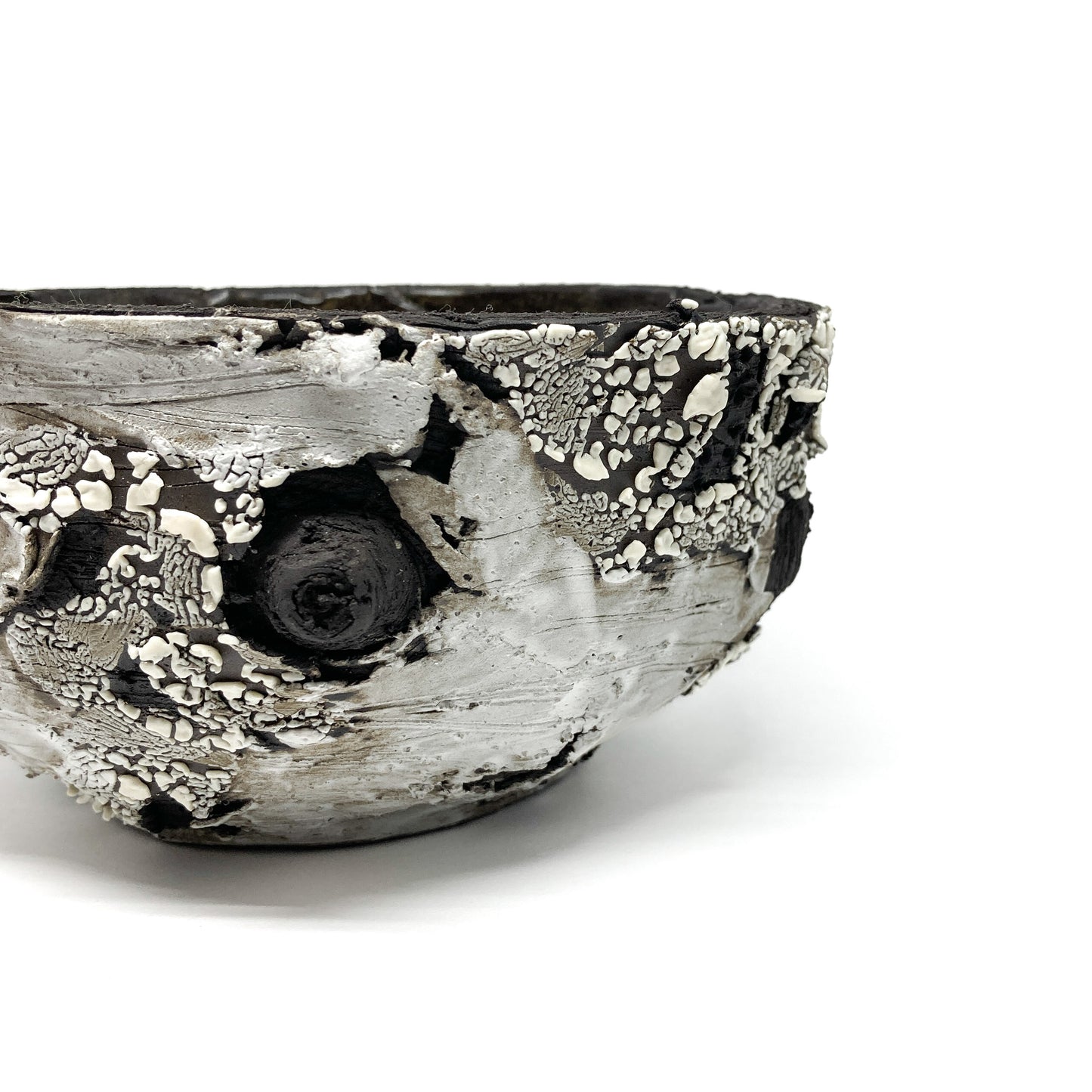 A close-up view of a small, round bowl with a textured surface, featuring black, white, and gray elements.