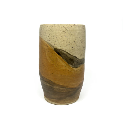 Speckled ceramic tumbler with layered earth-toned glazes in cream, gold, and brown.