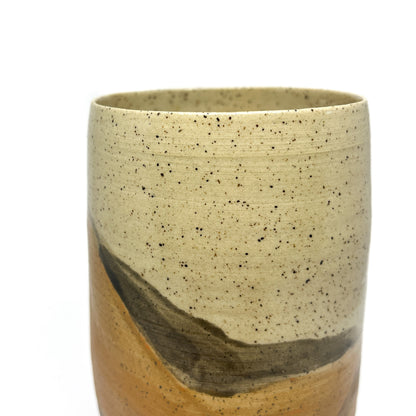 Speckled ceramic tumbler with a cream top and abstract washes of gold and brown glaze.