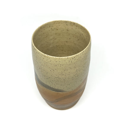 Speckled ceramic tumbler with a cream top and abstract washes of gold and brown glaze.