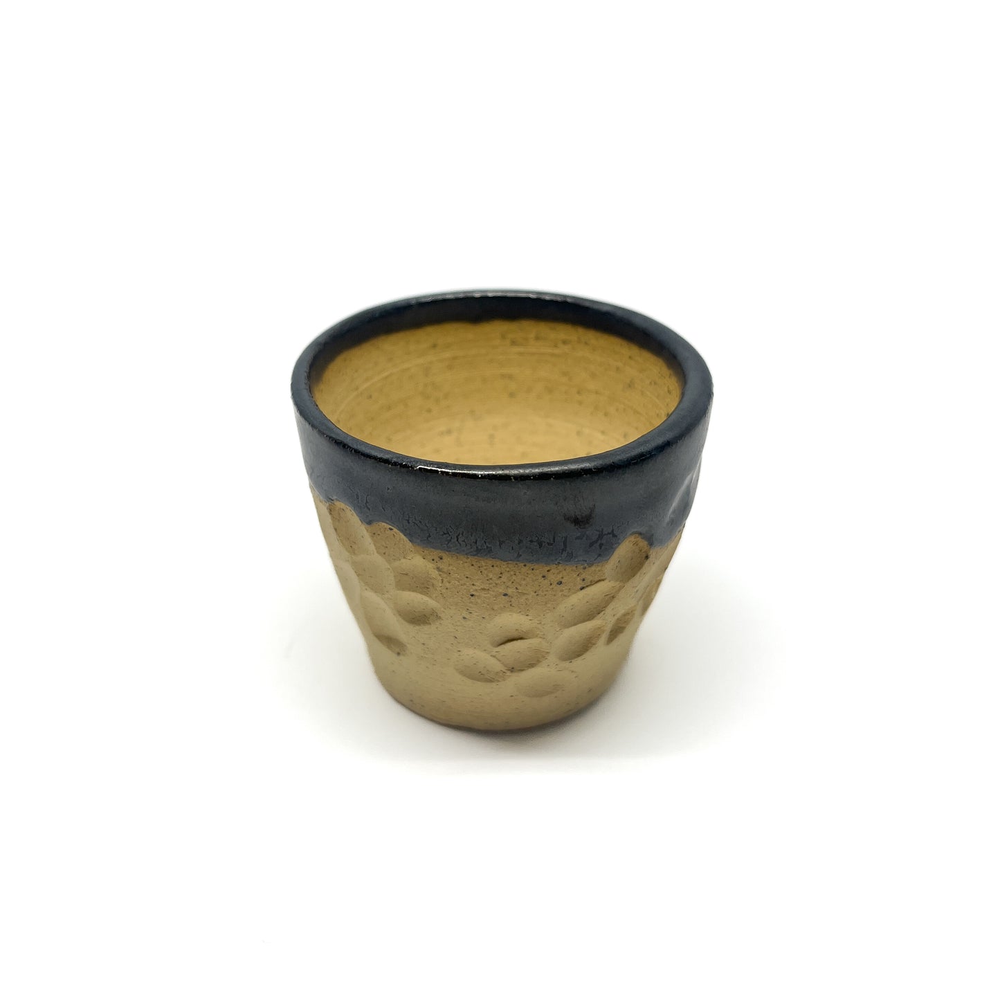 Small ceramic cup with a dark glazed rim over a textured, unglazed lower portion.