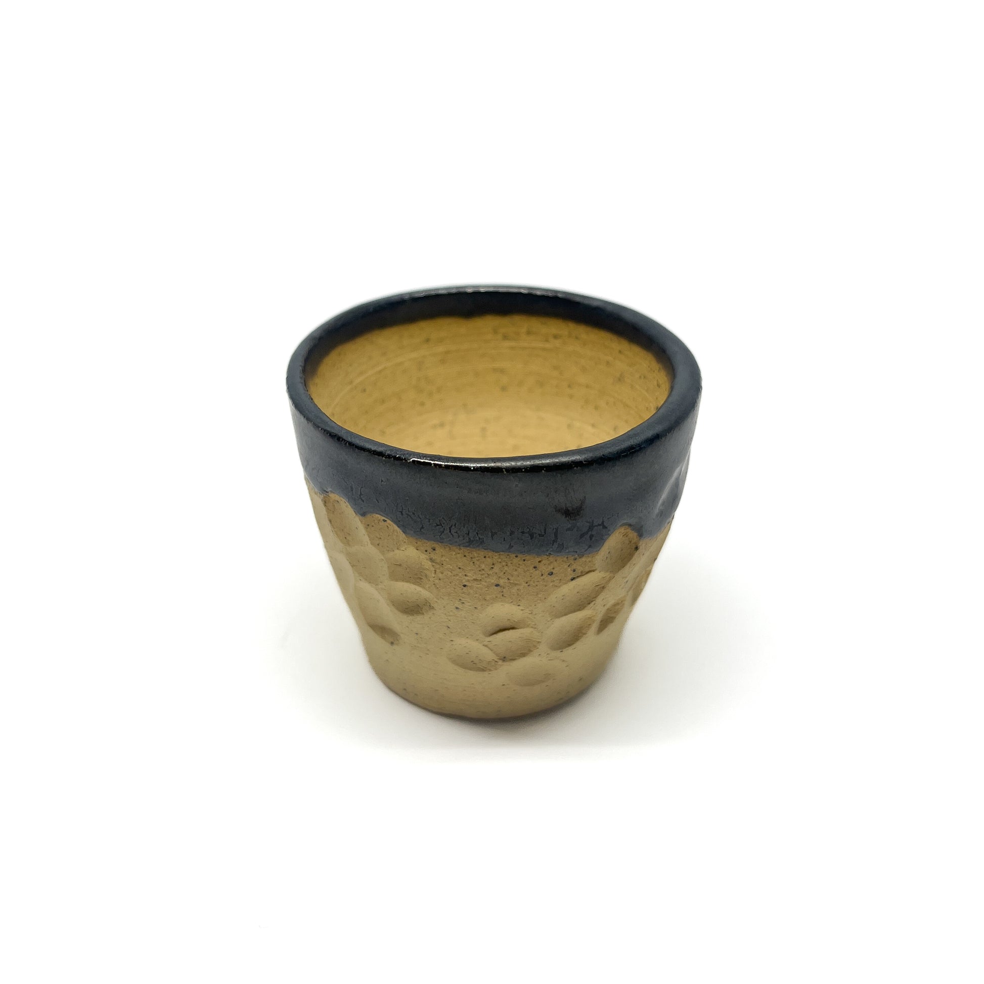 Small ceramic cup with a dark glazed rim over a textured, unglazed lower portion.