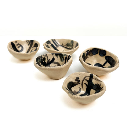 Five handmade Kana London pinch pots, each with unique black abstract markings inside.