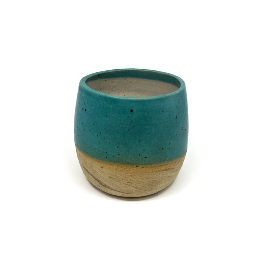 Small, speckled ceramic cup with a teal glazed top and a textured, unglazed base.