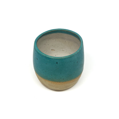 Speckled ceramic cup with a teal exterior glaze and a natural, unglazed bottom and interior.