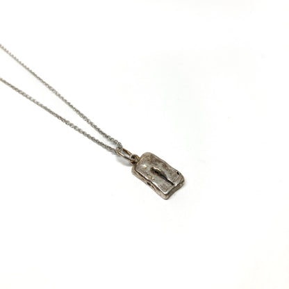 Single small silver pendant with an abstract etched design on a delicate chain.