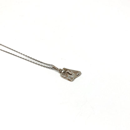 Angled close-up of a unique, small silver pendant.